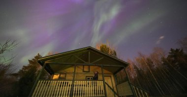 A woman watches northern lights over the village of Podolye, east of Saint Petersburg, Russia, April 23, 2023. (AP Photo)