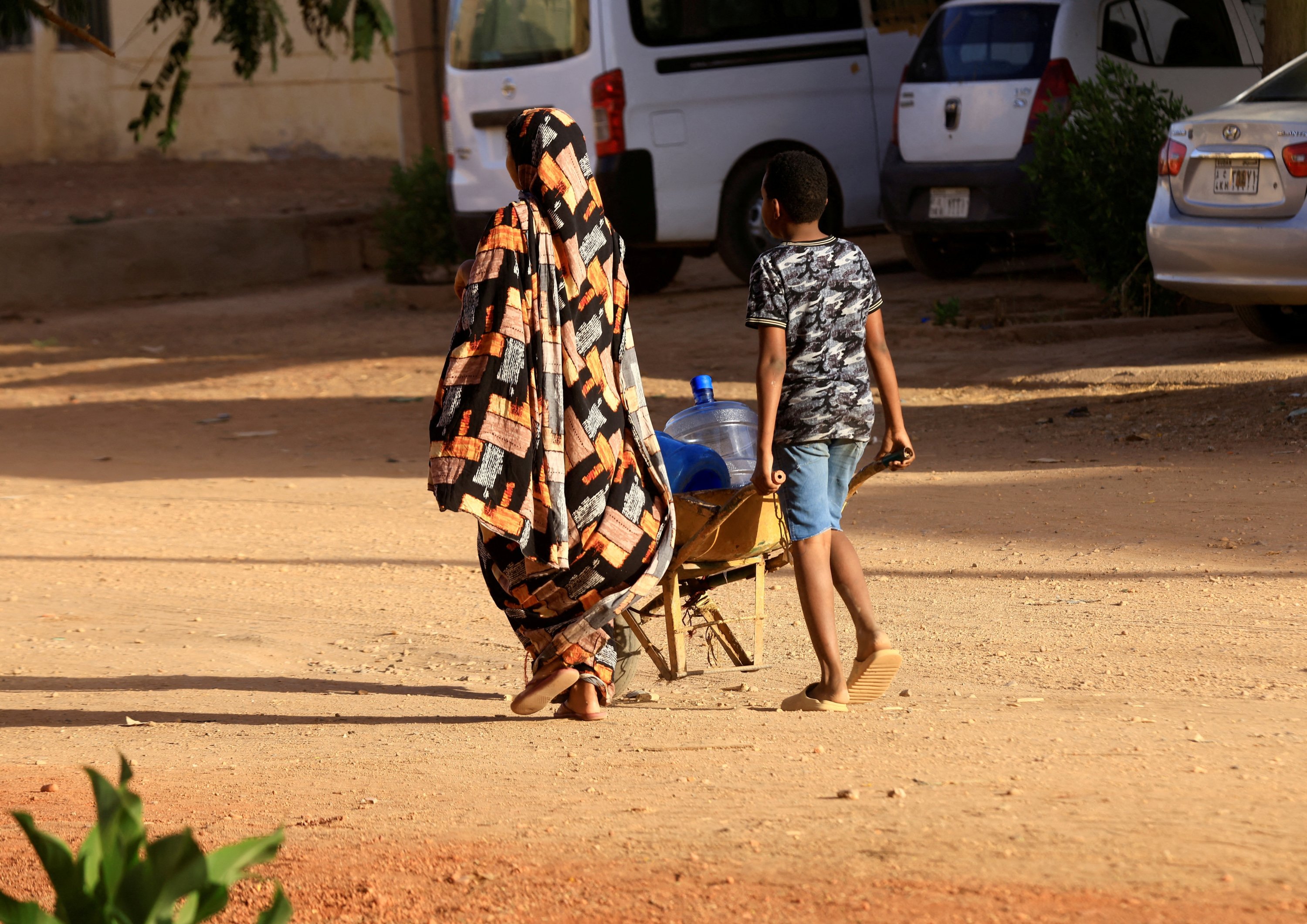 Orang-orang berjalan mencari air selama bentrokan antara Pasukan Dukungan Cepat paramiliter dan tentara di Khartoum, Sudan, 20 April 2023. (Foto Reuters)