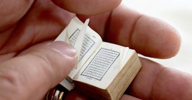 Mario Prushi holds in his hand one of the smallest Quran, Islam's holy book, of a postage-stamp-size with a cover crafted from gold embroidered velvet, in Tirana, Albania, April 17, 2023. (AFP Photo)