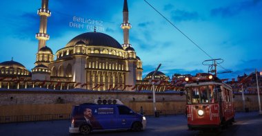 A tram passes by an election campaign car of President Recep Tayyip Erdoğan in front of Taksim Mosque in Istanbul, Türkiye, April 19, 2023. (EPA Photo)