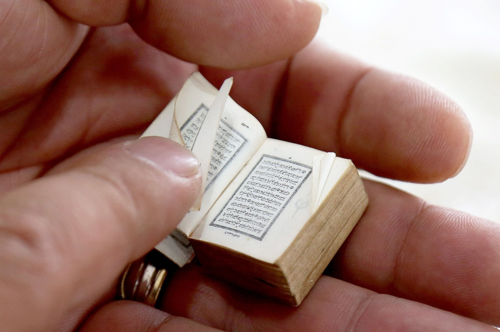 Mario Prushi holds in his hand one of the smallest Quran, Islam&#039;s holy book, of a postage-stamp-size with a cover crafted from gold embroidered velvet, in Tirana, Albania, April 17, 2023. (AFP Photo)