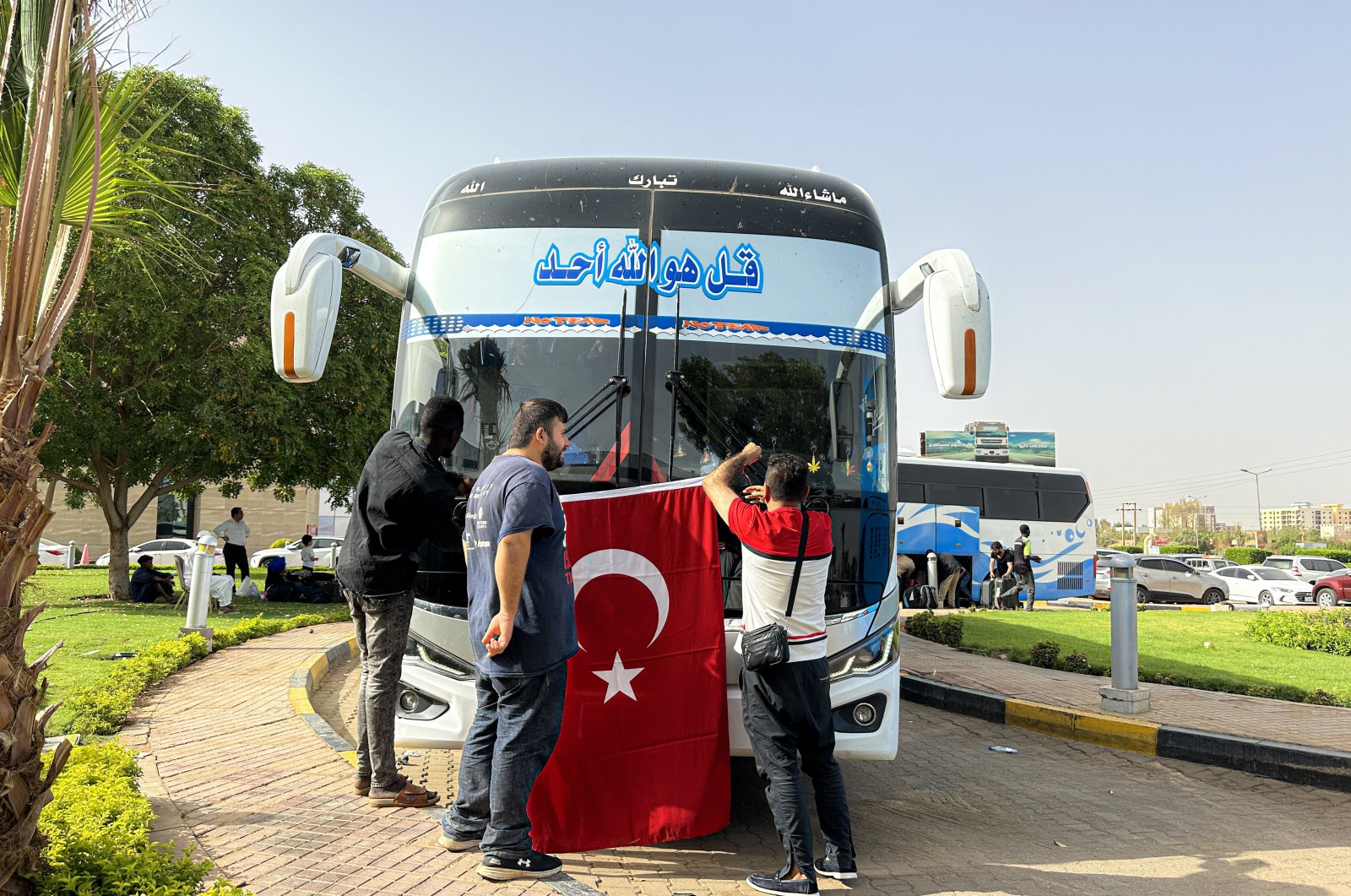 Two men hang up a Turkish flag in front of a bus that will carry a group of evacuees, including Turkish citizens, out of the country amid clashes, in the capital Khartoum, Sudan, April 27, 2023. (AA Photo)