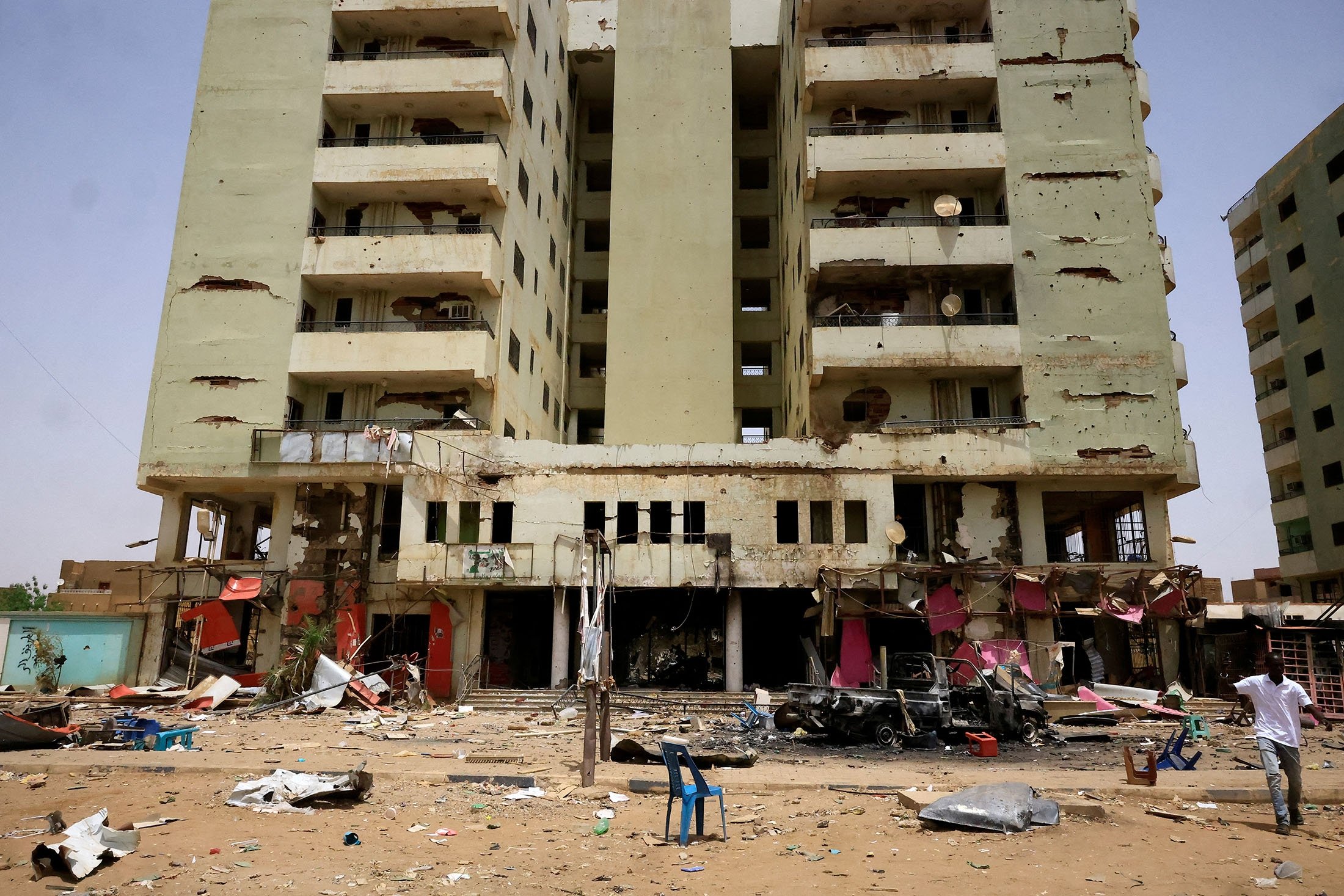 A man walks near a damaged car and buildings at the central market during clashes between the paramilitary Rapid Support Forces and the army in Khartoum, Sudan, April 27, 2023. (Reuters Photo)