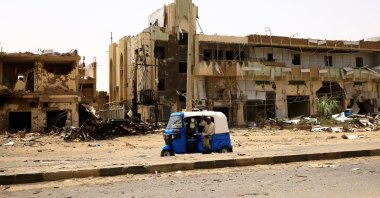 People pass by damaged cars and buildings at the central market during clashes between the paramilitary Rapid Support Forces and the army in Khartoum, Sudan, April 27, 2023. (Reuters Photo)