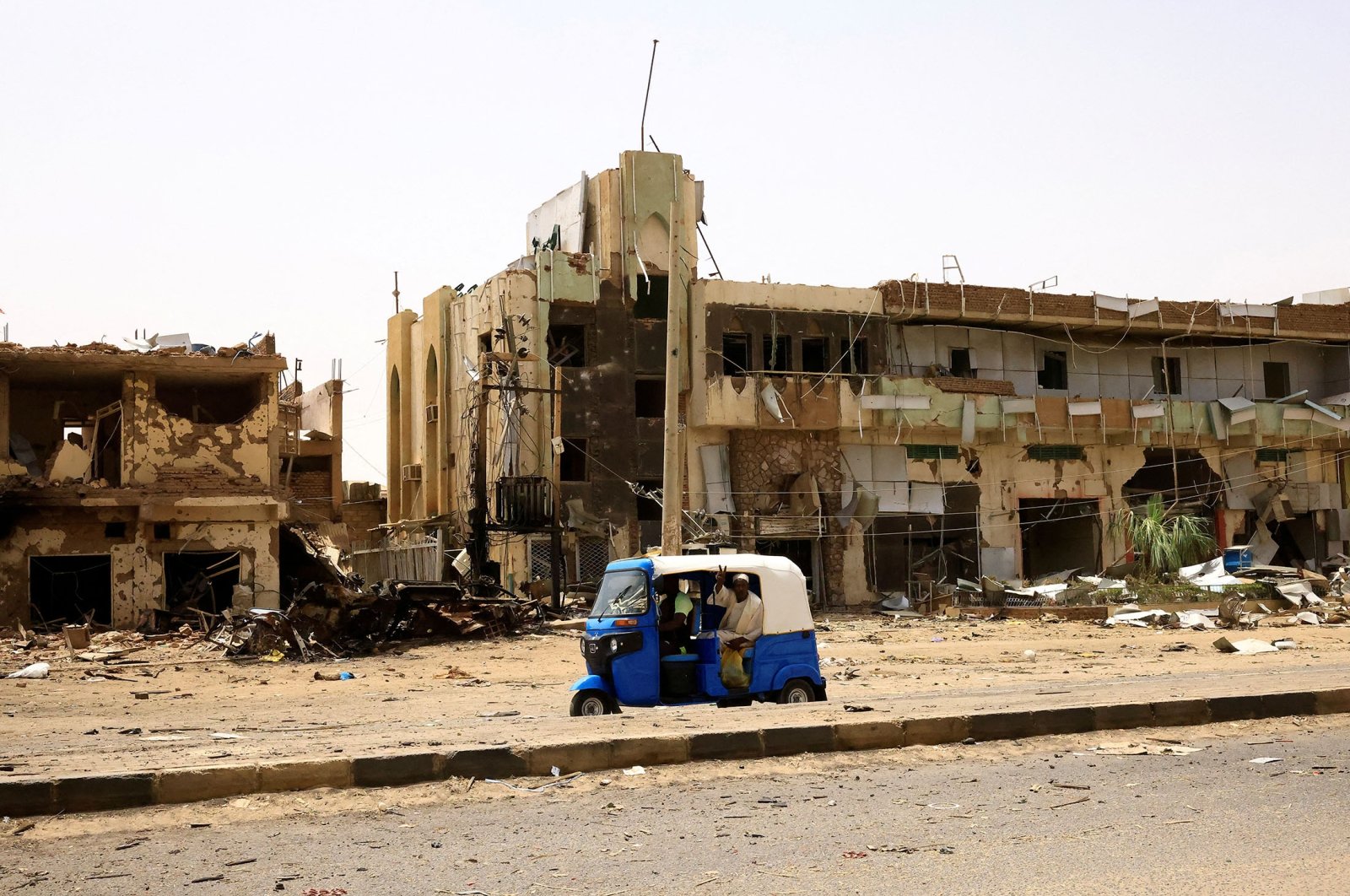 People pass by damaged cars and buildings at the central market during clashes between the paramilitary Rapid Support Forces and the army in Khartoum, Sudan, April 27, 2023. (Reuters Photo)