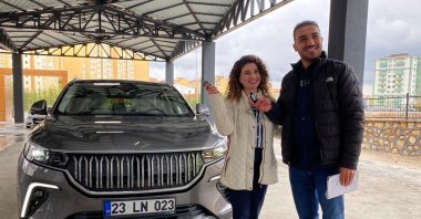 Mathematics teacher Turgay Akgün and his wife Ayça pose for a photo as they receive their Togg T10X, in Elazığ province, eastern Türkiye, April 30, 2023. (DHA Photo)