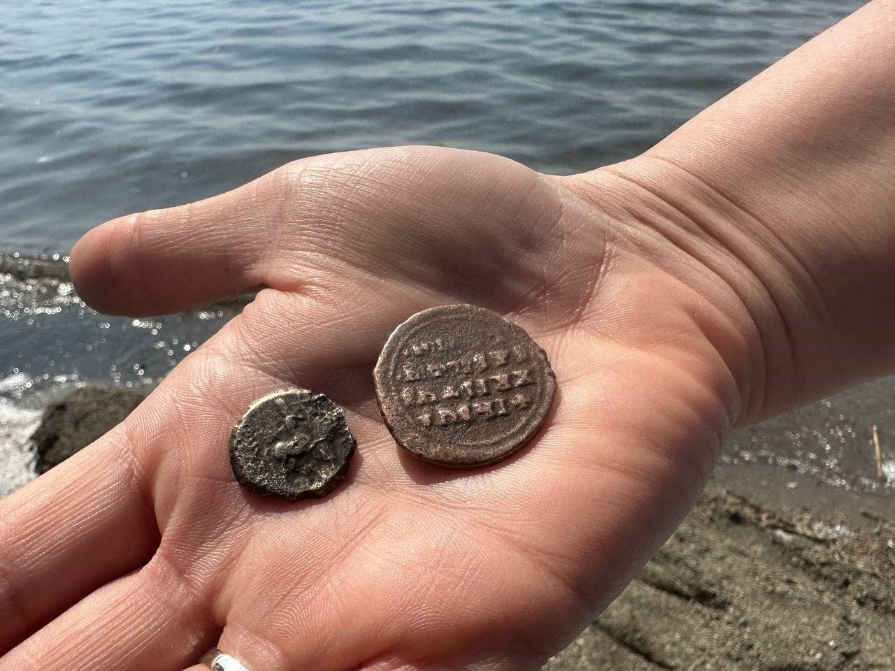 Ismail Yıldırım shows the 2,000-year-old coins he found on the shores of Lake Izinik, Bursa, Türkiye, May 2, 2023. (IHA Photo)