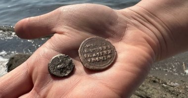 Ismail Yıldırım shows the 2,000-year-old coins he found on the shores of Lake Izinik, Bursa, Türkiye, May 2, 2023. (IHA Photo)