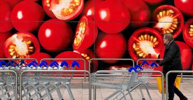 A shopper walks next to a photographic depiction of tomatoes in a Tesco supermarket as Britain experiences a seasonal shortage of some fruit and vegetables, in London, Britain, Feb. 26, 2023. (Reuters Photo)