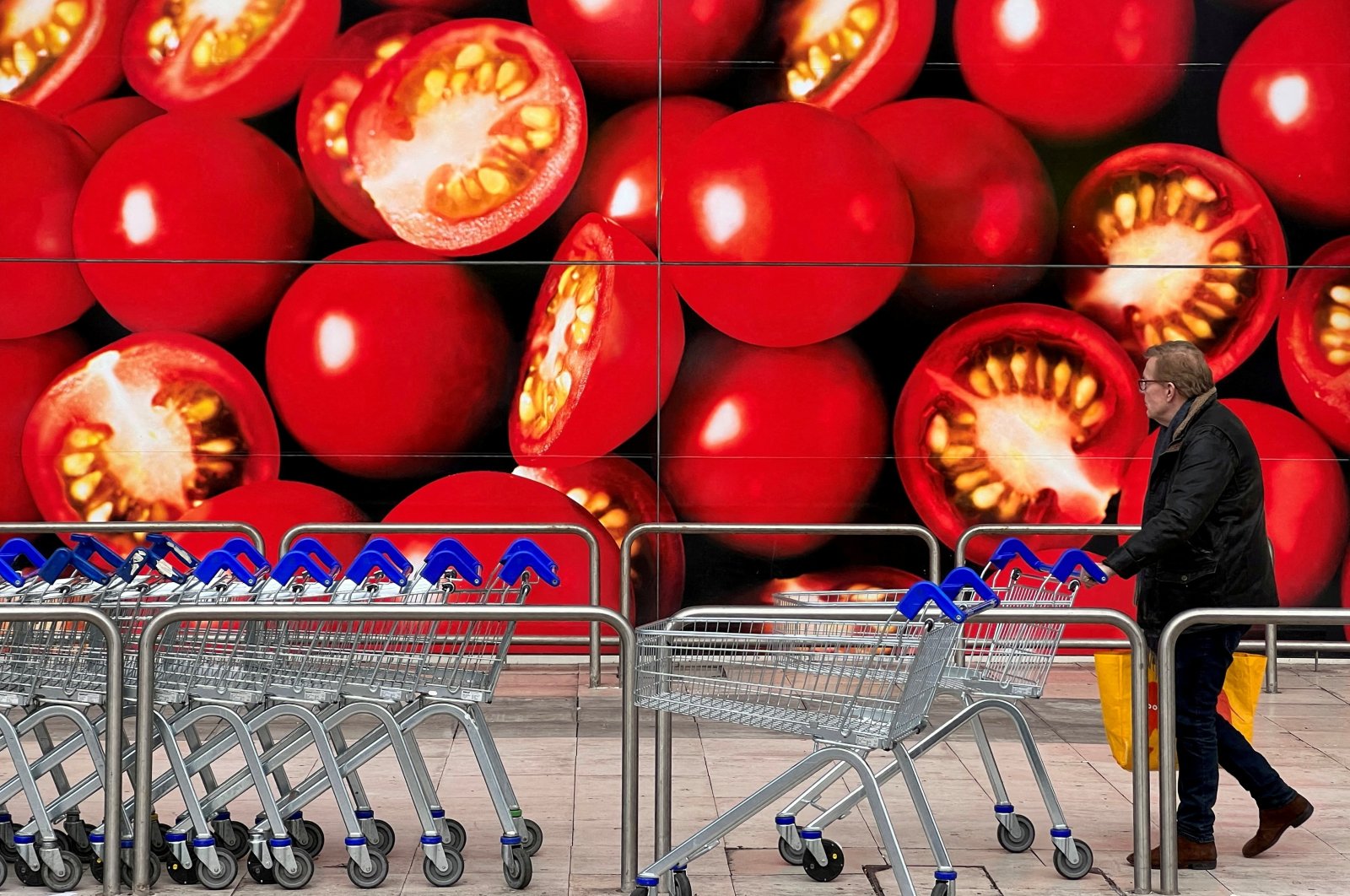 A shopper walks next to a photographic depiction of tomatoes in a Tesco supermarket as Britain experiences a seasonal shortage of some fruit and vegetables, in London, Britain, Feb. 26, 2023. (Reuters Photo)