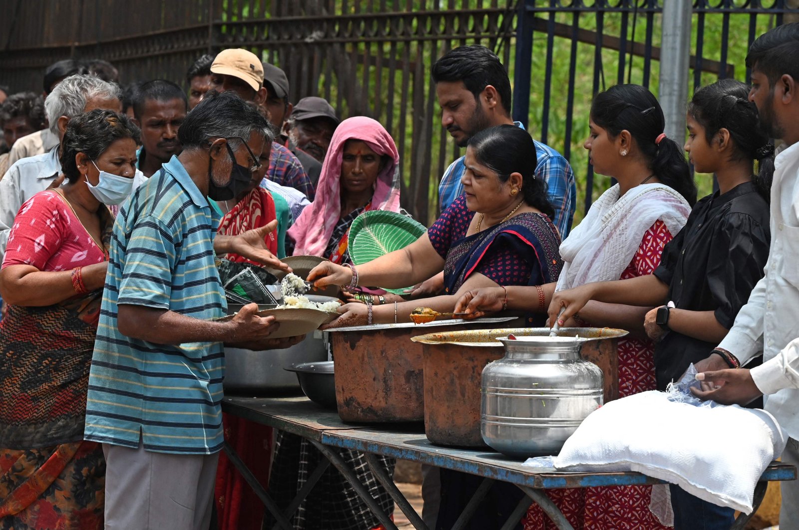 People stand in a queue as they receive free food distributed as a charity by volunteers along a street in Hyderabad, India, April 27, 2023. (AFP Photo)