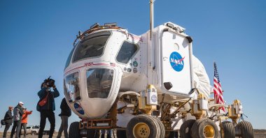 Members of the media stand next to a moon rover prototype for future Artemis missions at the Black Point Lava Flow near Flagstaff, Arizona, U.S., Oct. 24, 2022. (AFP Photo)