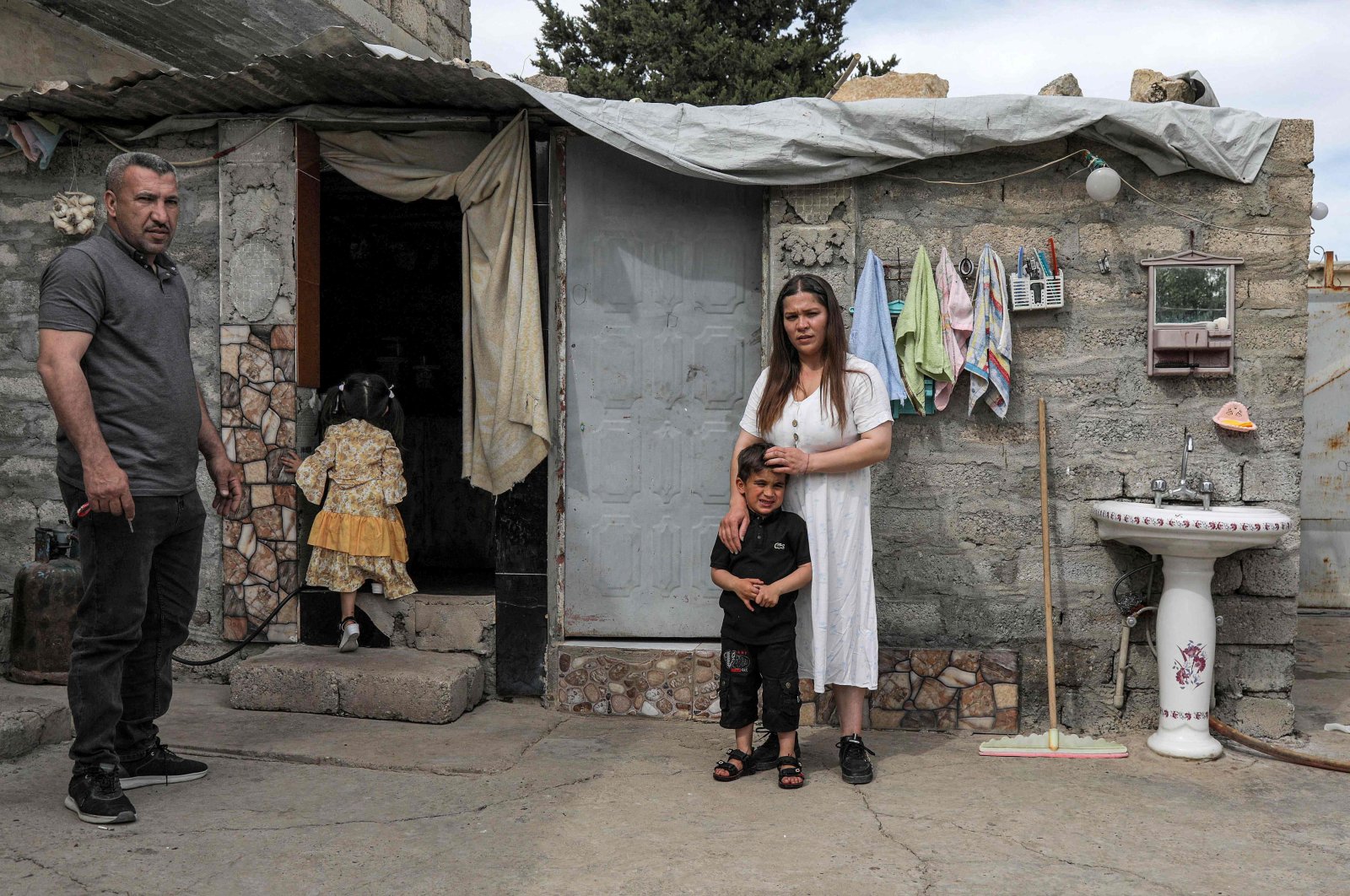 Hayam (R), a 26-year-old displaced Iraqi woman from the Yazidi community, poses for a picture outside a home during an interview with her husband Marwan and children in the region of Sharya, some 15 kilometers near the northern Iraqi city of Dohuk, April 19, 2023. (AFP Photo)