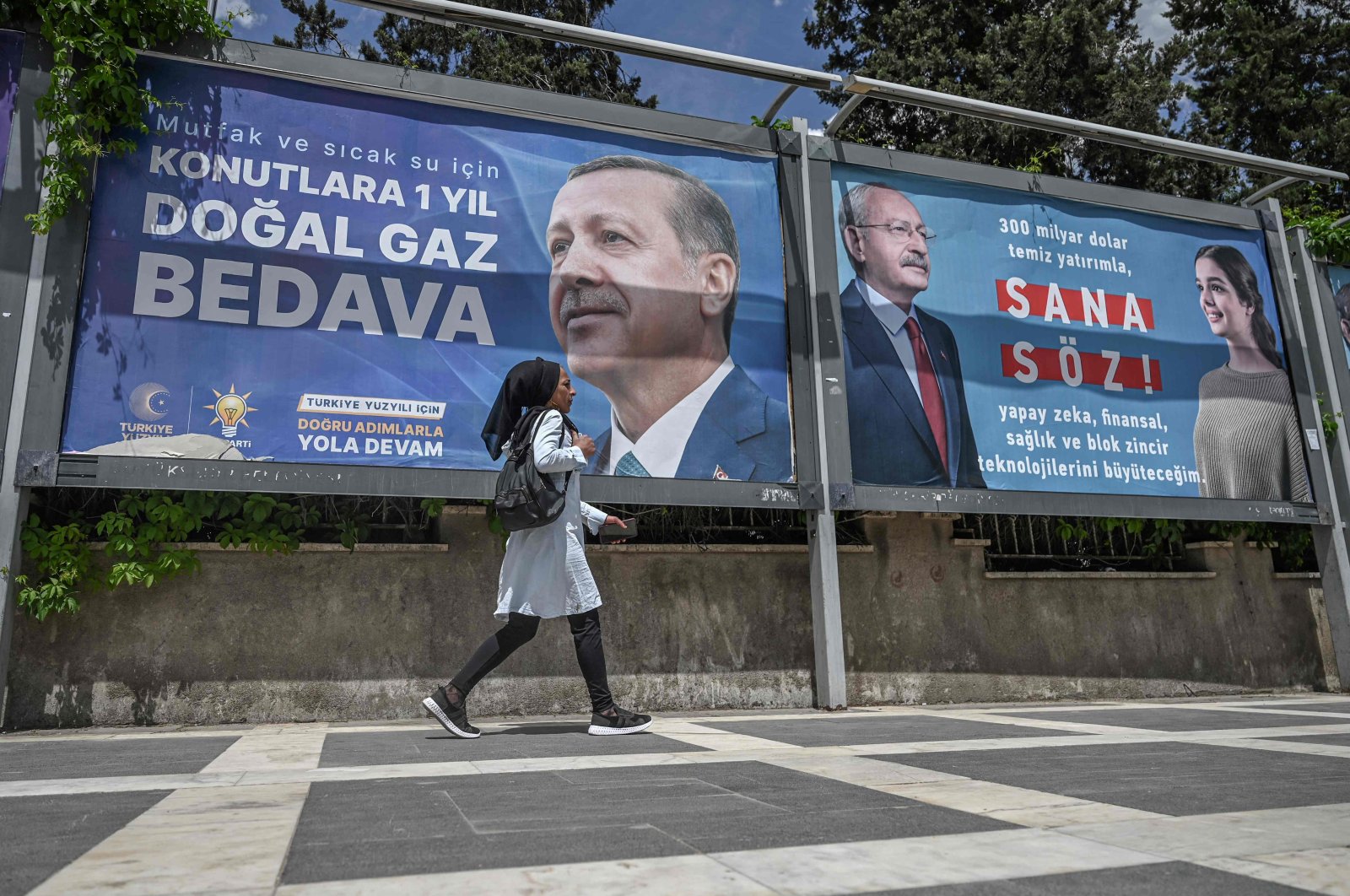 A Syrian woman walks past billboards of incumbent President Recep Tayyip Erdoğan (L) and Kemal Kılıçdaroğlu, in Şanlıurfa, April 28, 2023. (AFP Photo)