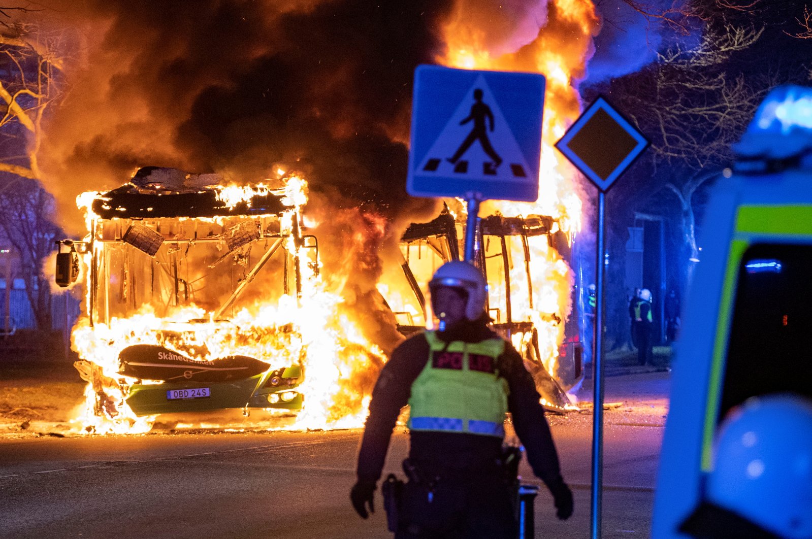 A police officer stands near a burning bus after a demonstration organized by Rasmus Paludan, leader of Danish far-right political party Hard Line turned violent, in Rosengard, Malmo, Sweden April 16, 2022. (Reuters File Photo)