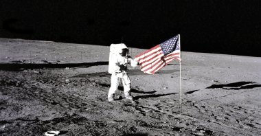Apollo 12 astronaut Charles Conrad stands beside the United States flag unfurled by Apollo 11 astronauts on the moon, Space, Nov. 19, 1969. (Getty Images Photo)