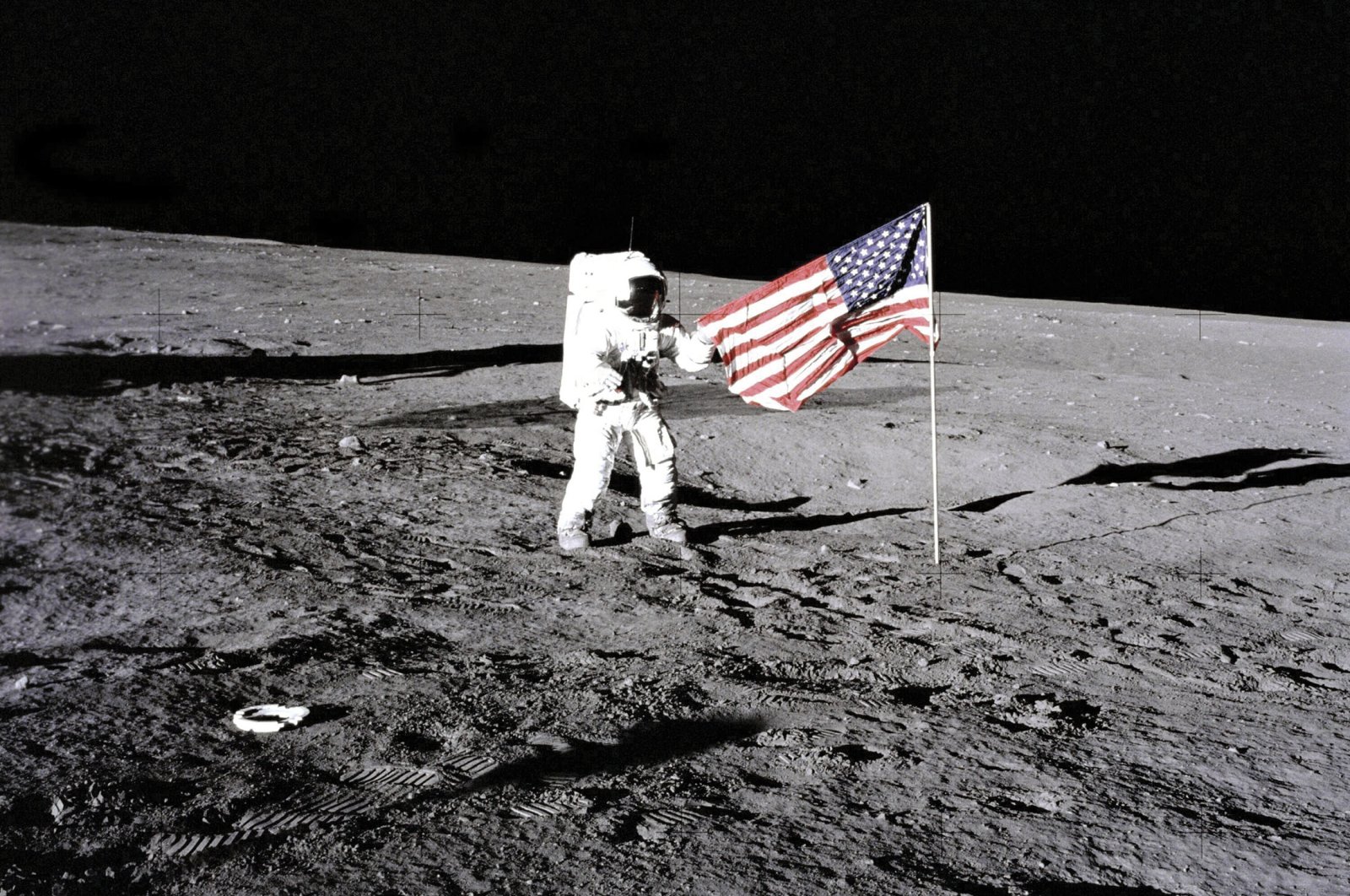Apollo 12 astronaut Charles Conrad stands beside the United States flag unfurled by Apollo 11 astronauts on the moon, Space, Nov. 19, 1969. (Getty Images Photo)