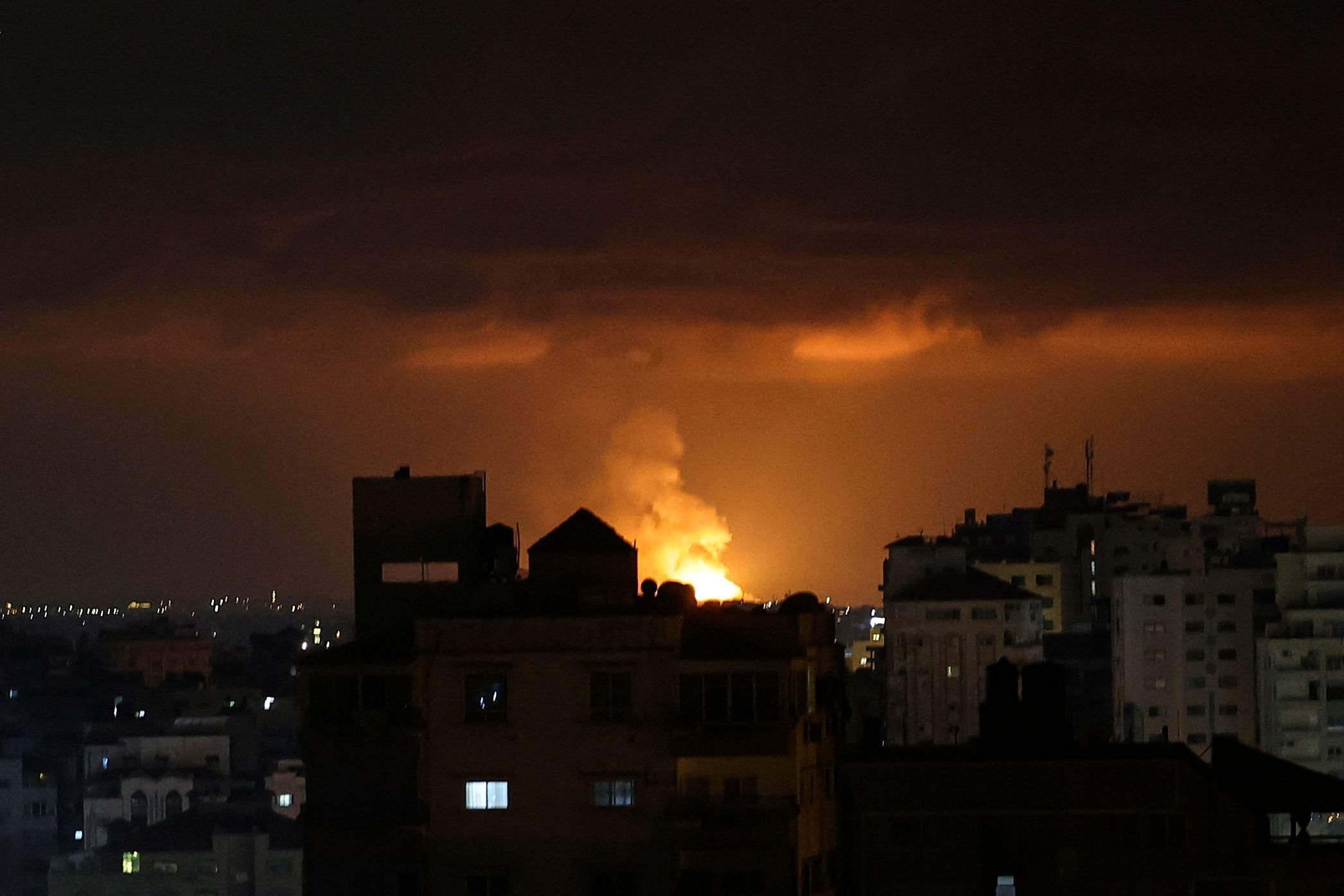Asap dan api mengepul di atas gedung-gedung setelah serangan udara Israel di Kota Gaza, Wilayah Palestina, 9 Mei 2023. (Foto AFP)