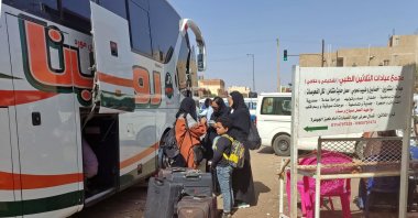People wait with their luggage at a bus stop in southern Khartoum as fighting continues between Sudan's army and the paramilitary forces, May 8, 2023. (AFP Photo)