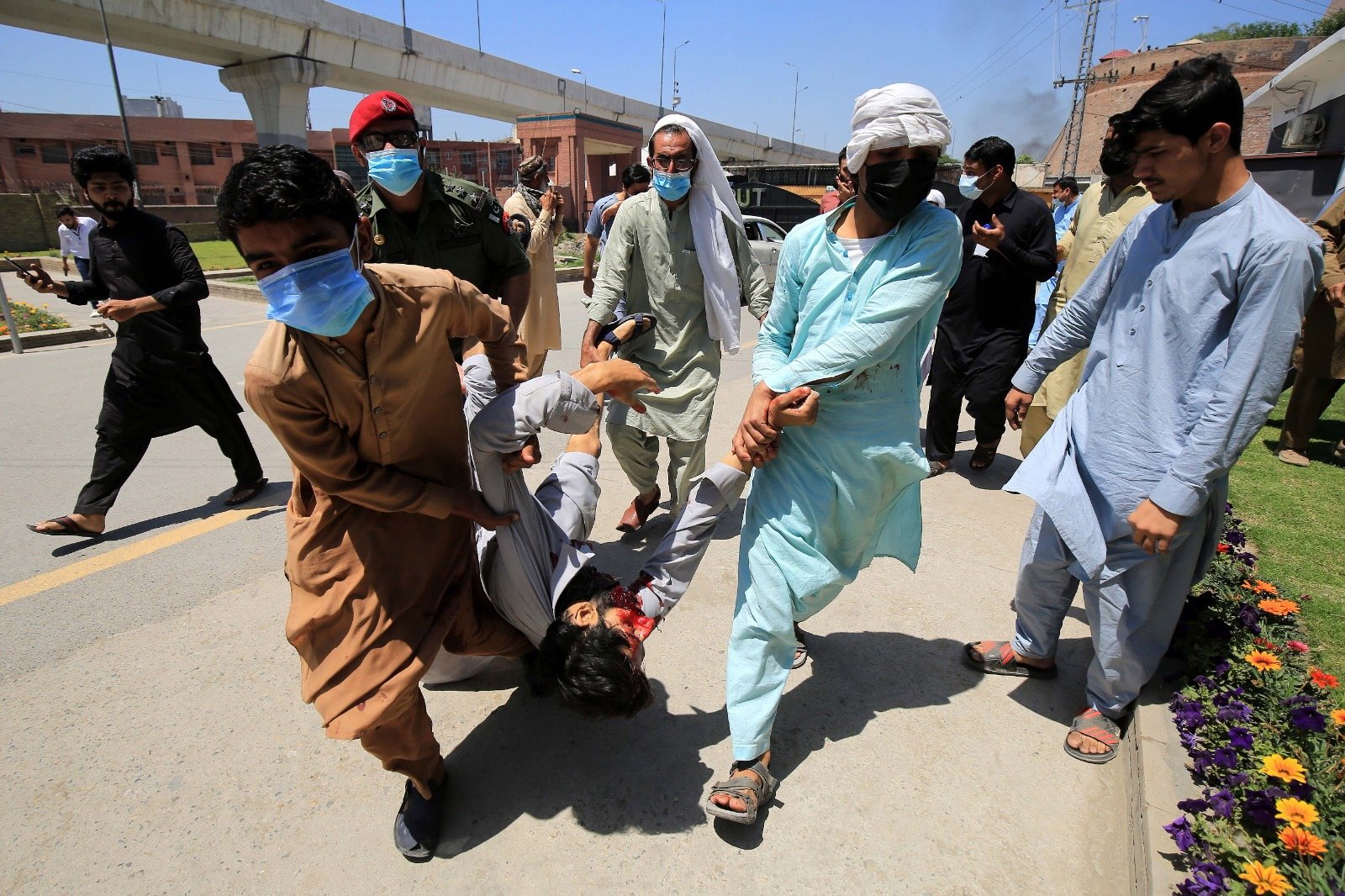 Seorang pria terluka dibawa pergi sebagai pendukung mantan Perdana Menteri Pakistan Imran Khan setelah bentrok dengan polisi di Peshawar, Pakistan, 10 Mei 2023. (Foto EPA)