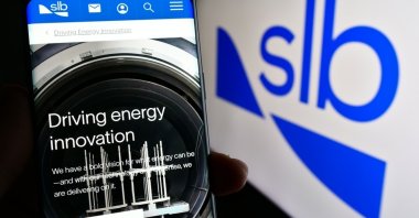 A person holding a cellphone with the webpage of oilfield company Schlumberger Limited (SLB) on screen in front of the logo, Stuttgart, Germany, Sept.3, 2023. (Shutterstock Photo)