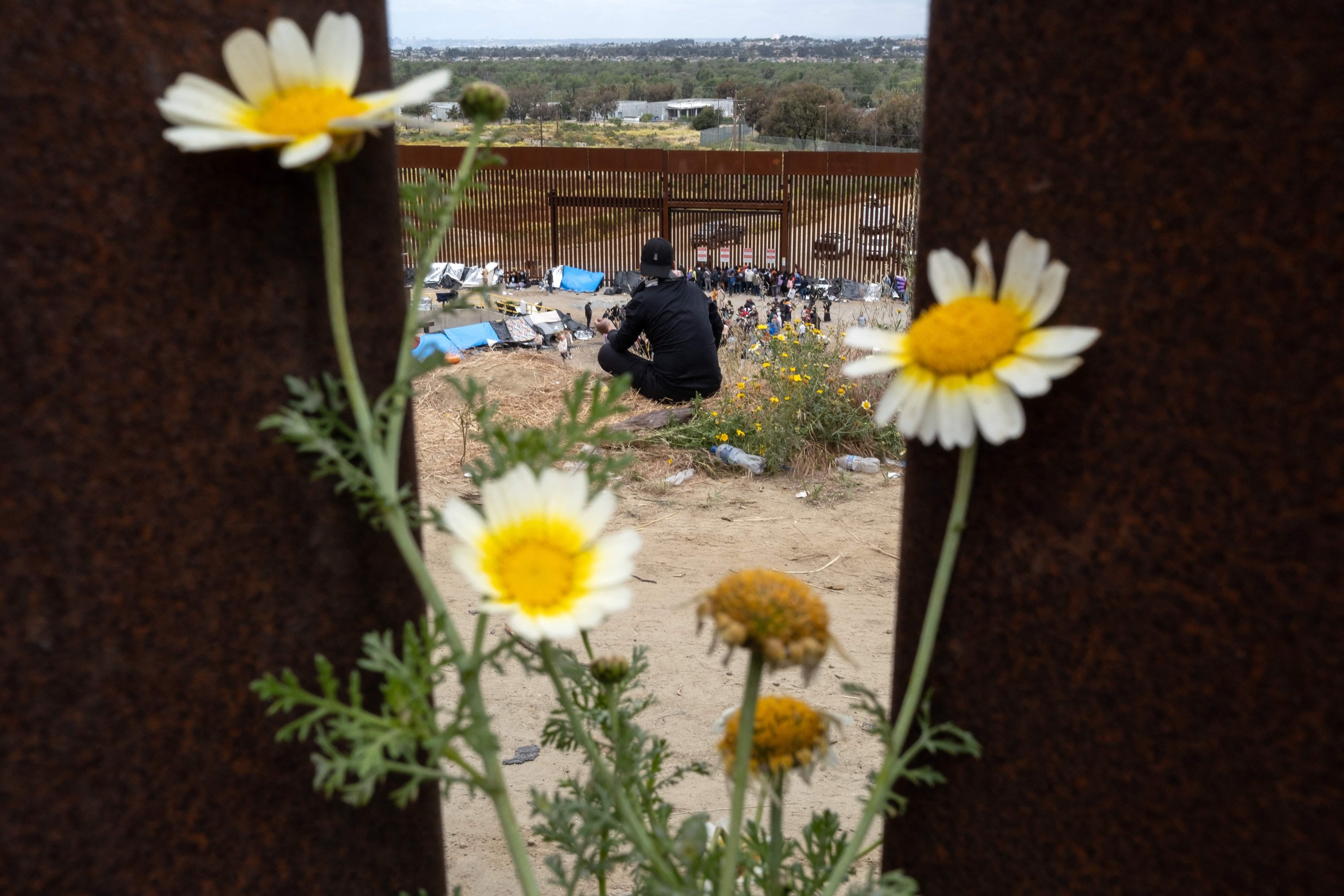 Migran menunggu untuk diproses oleh otoritas AS di perbatasan AS-Meksiko sisi AS dilihat dari Tijuana, negara bagian Baja California, Meksiko, 10 Mei 2023. (Foto AFP)