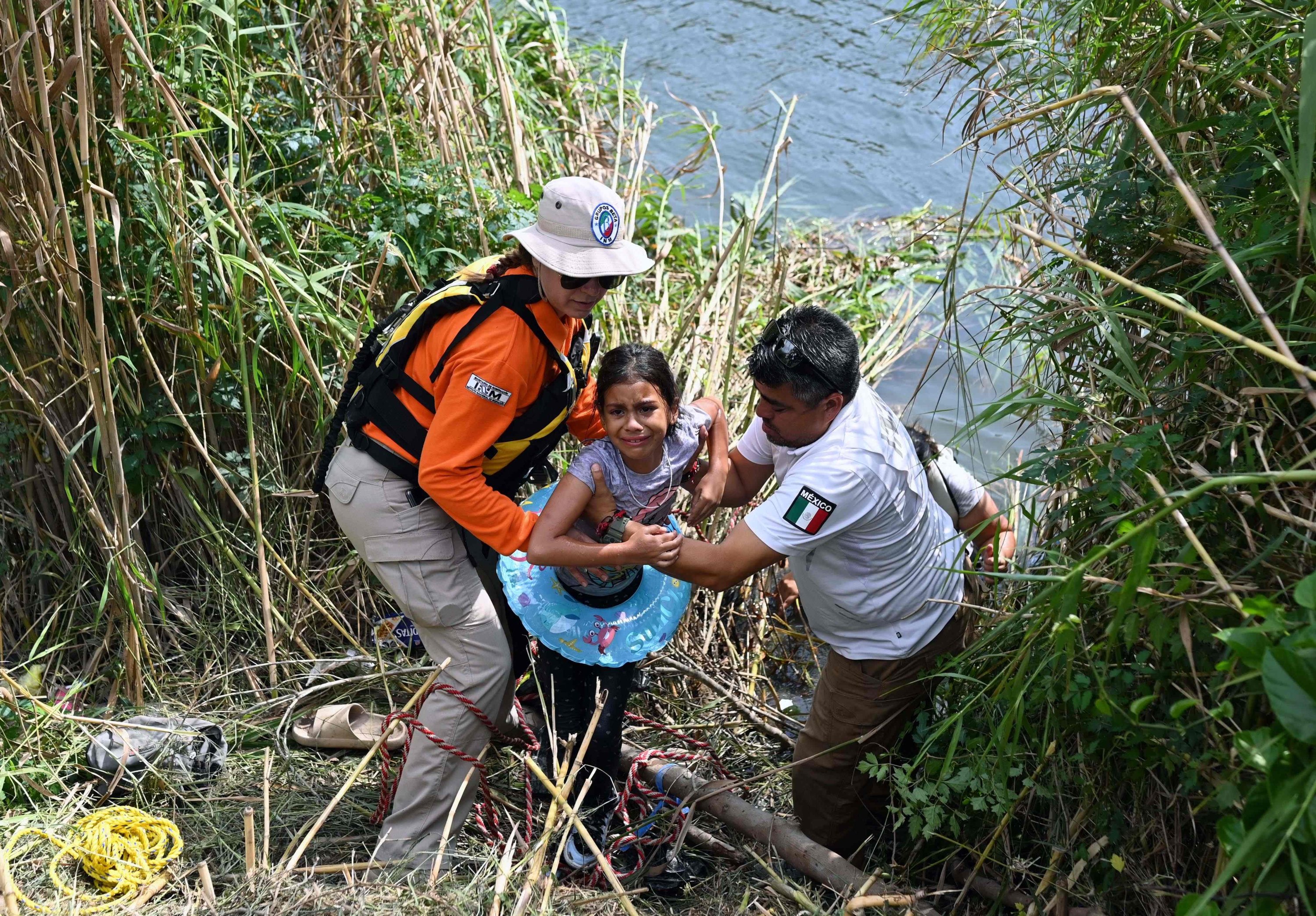 Anggota Grup Beta Pemerintah Meksiko membantu seorang gadis migran di Matamoros, negara bagian Tamaulipas, Meksiko, 10 Mei 2023. (Foto AFP)