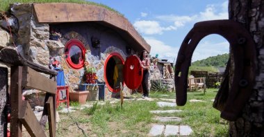 Marija Milicevic opens a door to a hobbit house named "Ober," in the Bosnian Hobbiton village, Rakova Noga, Bosnia-Herzegovina, May 9, 2023. (Reuters Photo)