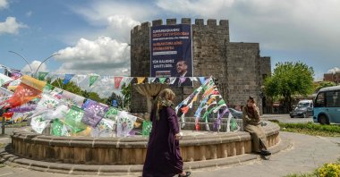 A woman walks past election campain flags of the pro-PKK Peoples' Democratic Party (HDP) and a banner with a portrait of President Recep Tayyip Erdogan hanging on historical Sur castle at the historical Sur district in Diyarbakir, southeastern Türkiye, May 1, 2023. (AFP Photo)