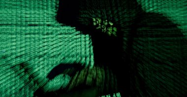 A man holds a laptop computer as cyber code is projected on him in this illustration picture taken on May 13, 2017. (Reuters Photo)