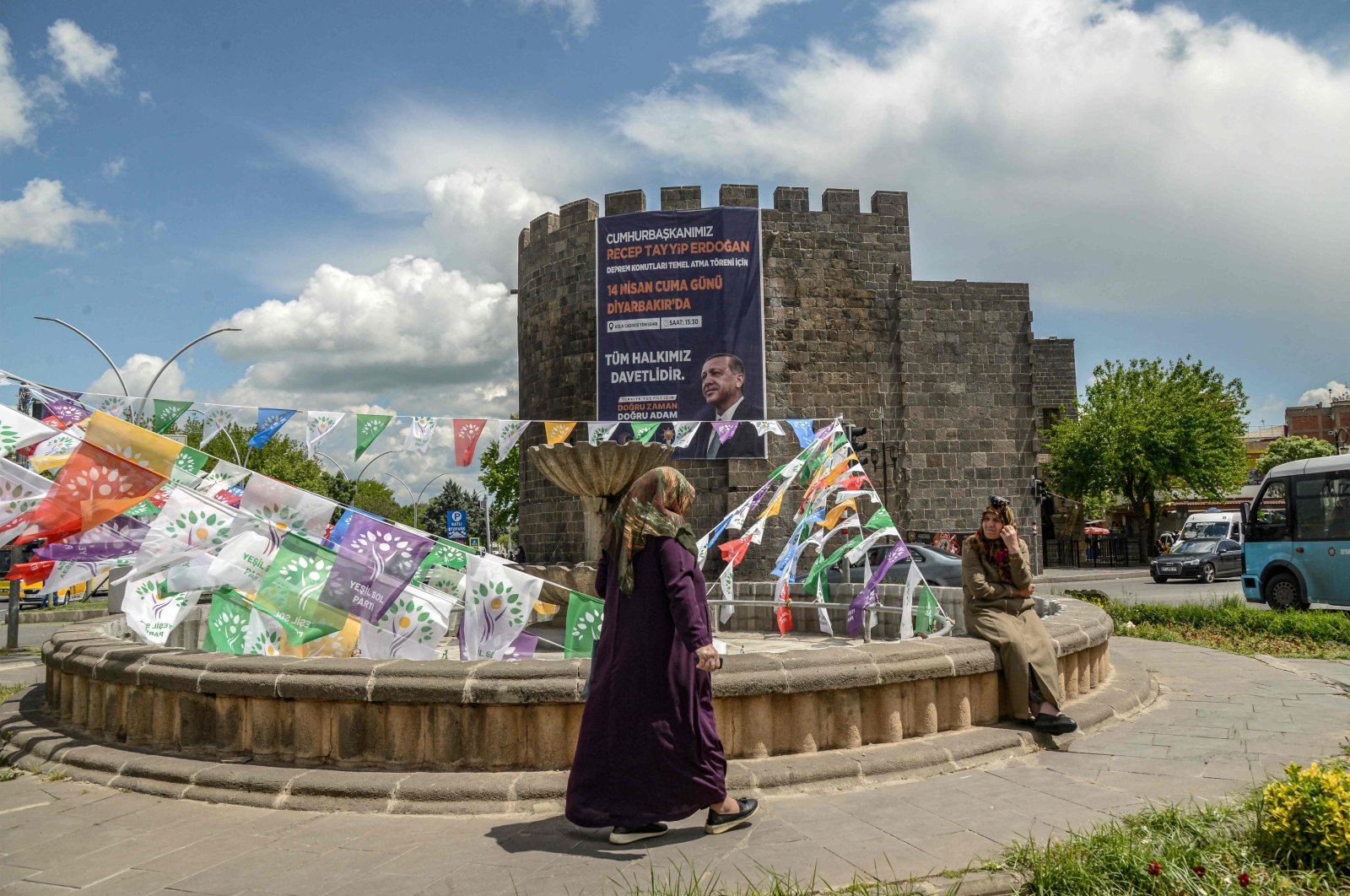 A woman walks past election campain flags of the pro-PKK Peoples&#039; Democratic Party (HDP) and a banner with a portrait of President Recep Tayyip Erdogan hanging on historical Sur castle at the historical Sur district in Diyarbakir, southeastern Türkiye, May 1, 2023. (AFP Photo)