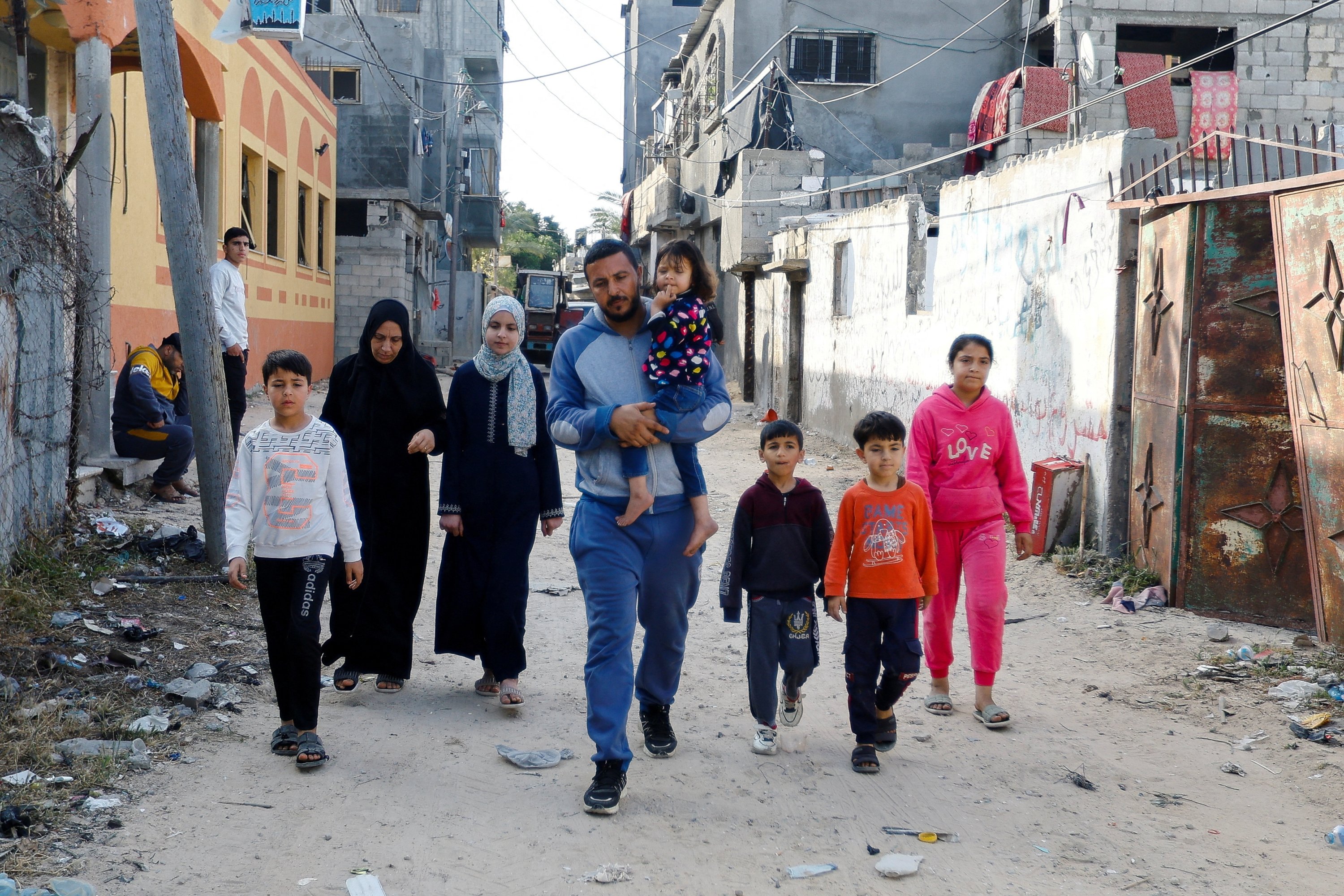 Warga Palestina berjalan saat mereka kembali ke rumah mereka, yang rusak akibat serangan Israel setelah gencatan senjata disepakati antara faksi Palestina dan Israel, Deir al-Balah, Jalur Gaza, Palestina, 14 Mei 2023. (Foto Reuters)
