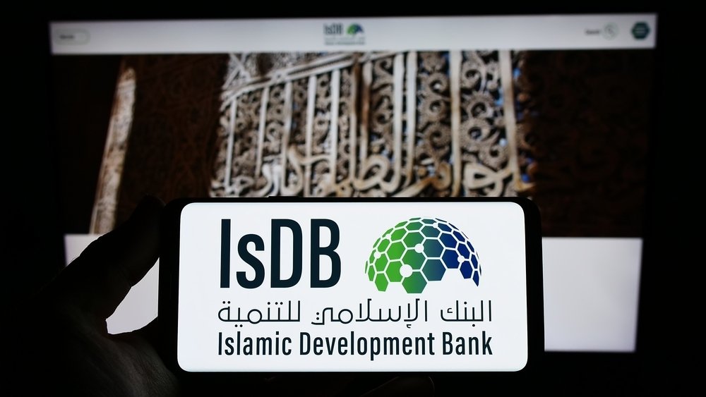 A person holds smartphone with logo of Islamic Development Bank (IsDB) on screen in front of website in Stuttgart, Germany, March 19, 2023. (Shutterstock Photo)
