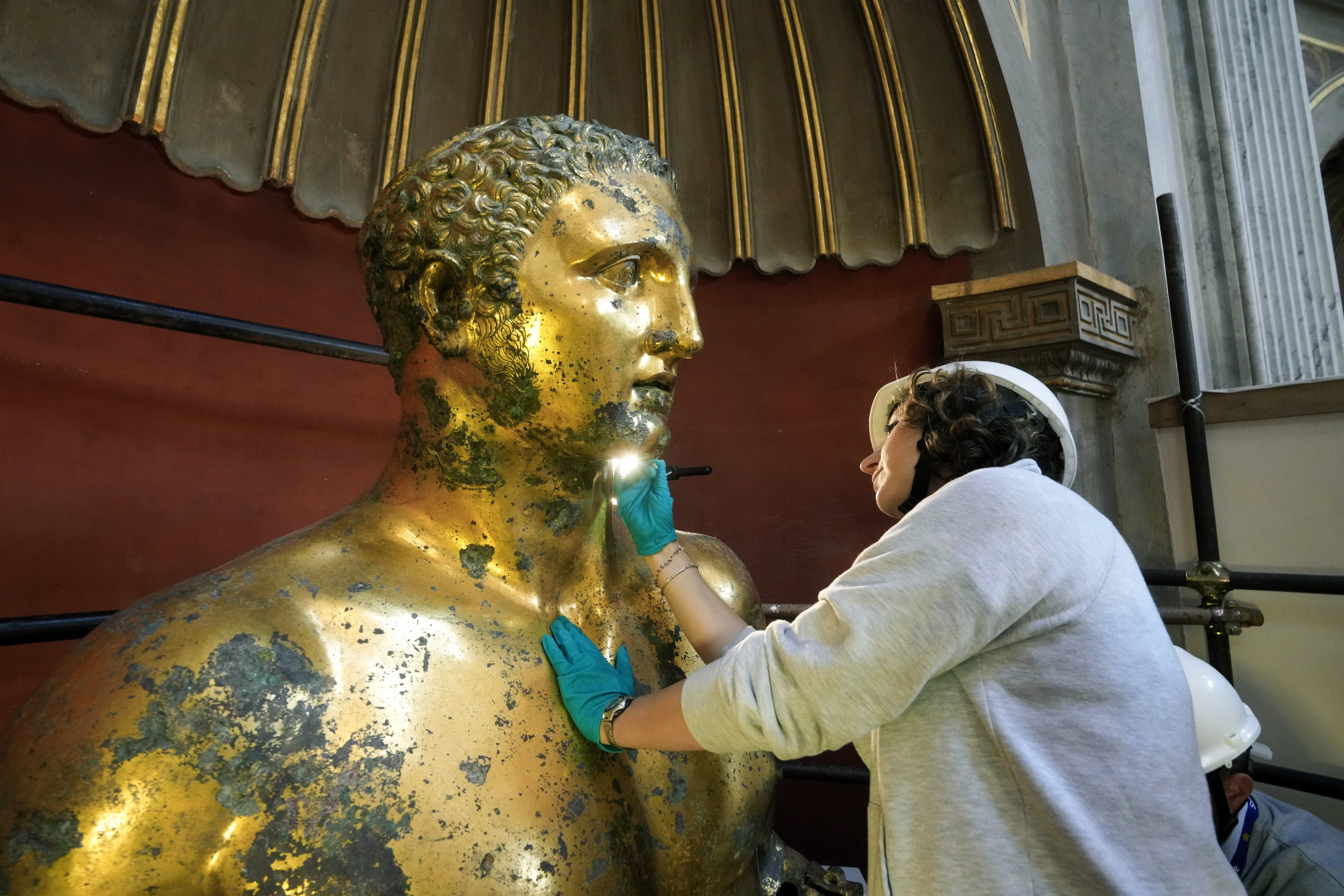 Pemulih Museum Vatikan Alice Baltera mengerjakan patung perunggu Hercules, di Aula Bundar Museum Vatikan, Vatikan, 11 Mei 2023. (Foto AP)