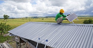 Antonius Makambombu, a worker of Sumba Sustainable Solutions performs maintenance work on a solar panel on the roof of a customer's shop in Laindeha village on Sumba Island, Indonesia, March 22, 2023. (AP Photo)