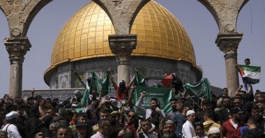 Palestinians hold the Palestinian national flag and the flag of the Hamas militant group during a protest by the Dome of Rock at the Al-Aqsa Mosque compound during the Muslim holy month of Ramadan, in the Old City of Jerusalem, Palestine, April 7, 2023. (AP Photo)