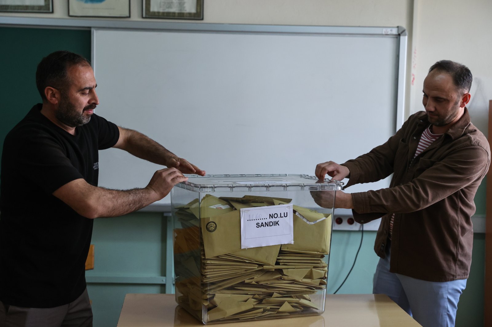 Two election officials secure the lid of a ballot box for the presidential and parliamentary elections after voting ends in western Izmir province, Türkiye, May 14, 2023. (AA Photo)