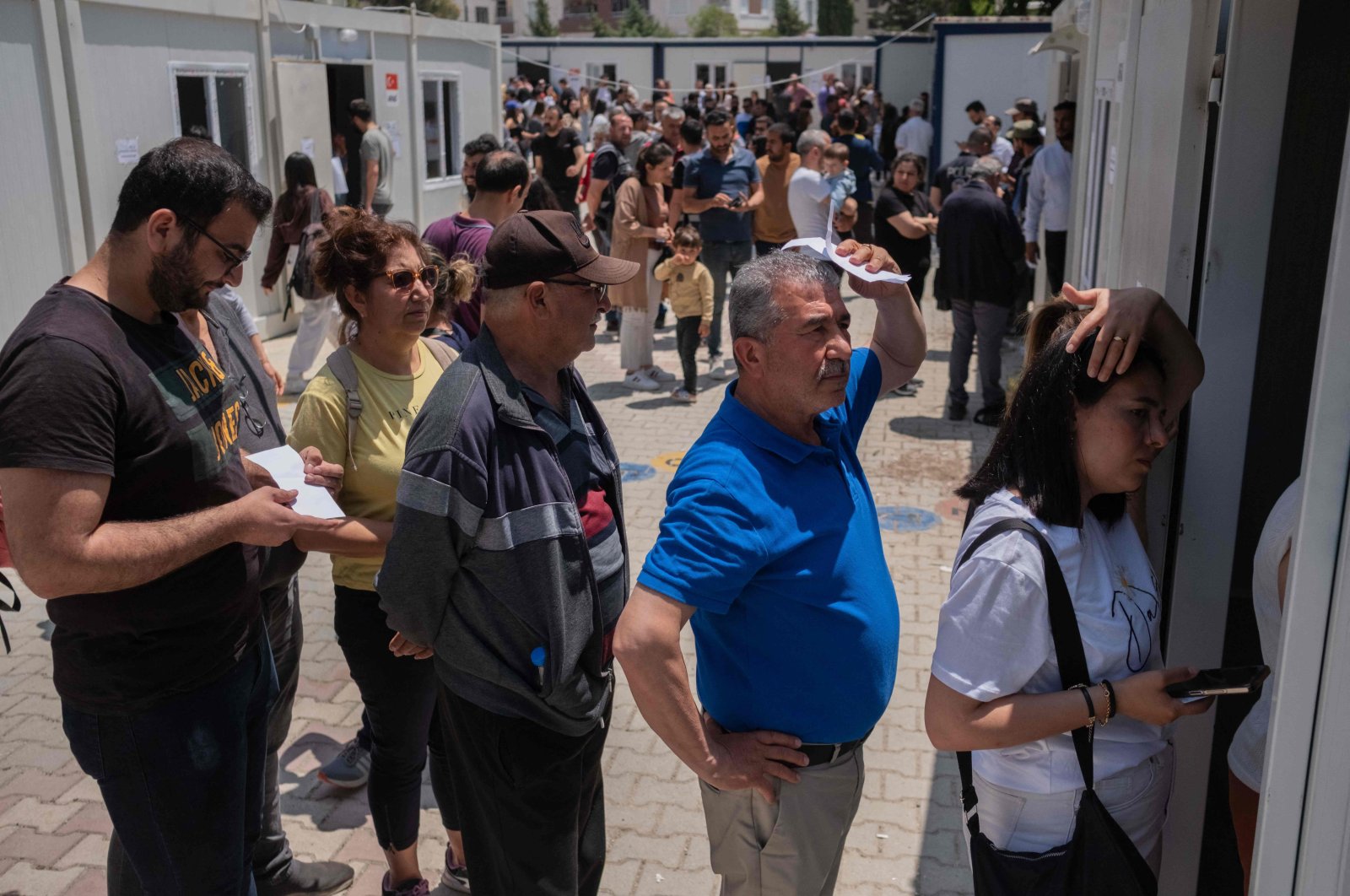 People line up to vote outside containers acting as improvised polling stations during the presidential and parliamentary elections in the southern city of Hatay, which was destroyed by this year&#039;s devastating earthquake, Türkiye, May 14, 2023. (AFP Photo)