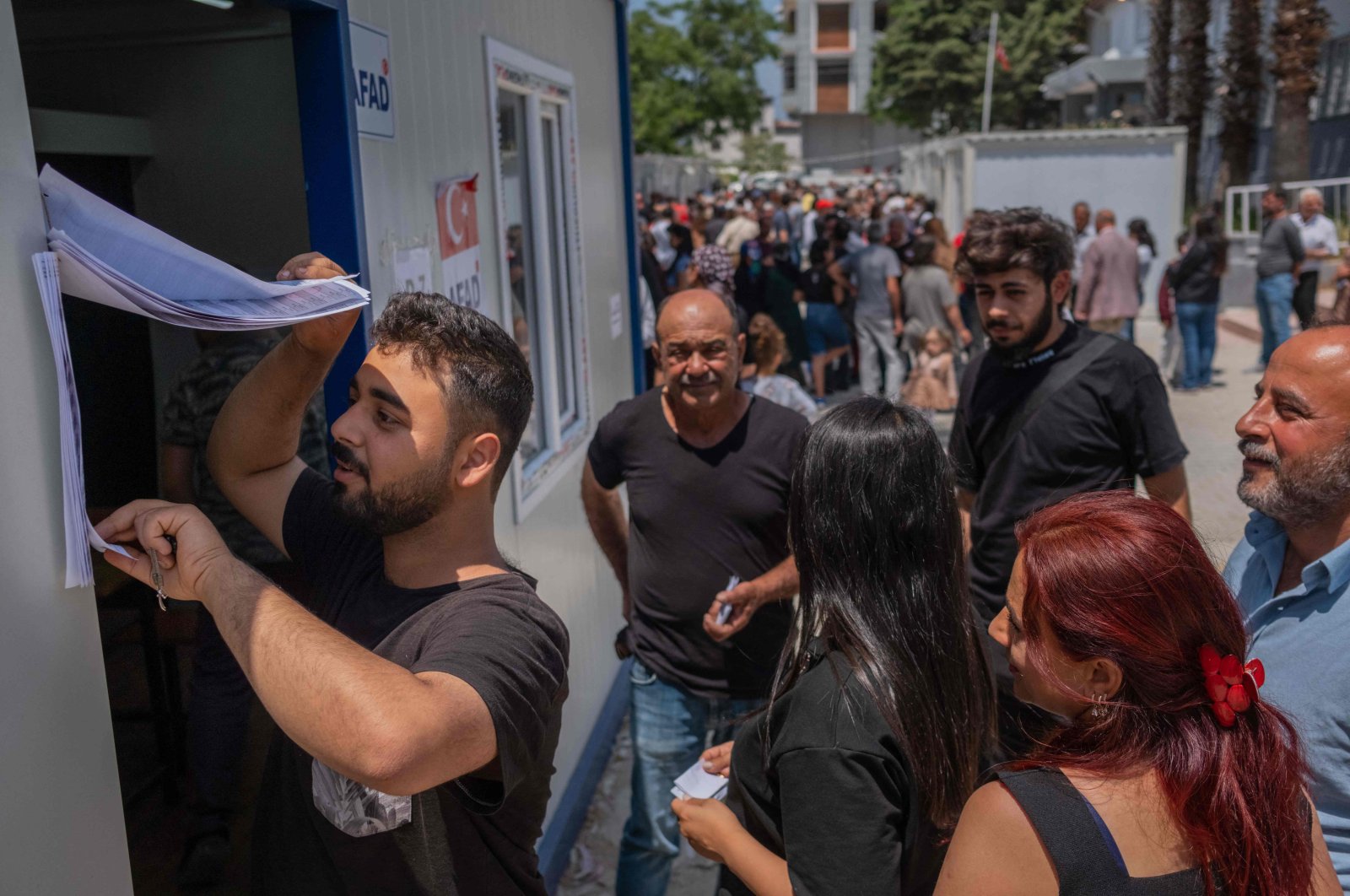 People queue to vote outside containers acting as polling stations during the presidential and parliamentary elections in the southern Turkish city of Antakya, destroyed by this year&#039;s devastating earthquake on May 14, 2023. (AFP Photo)