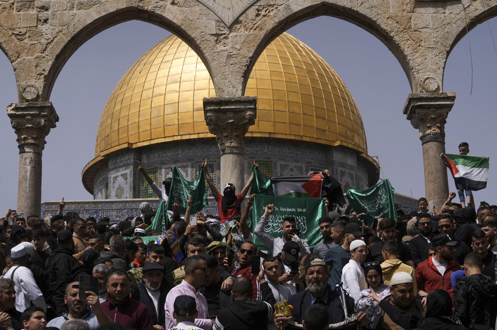 Palestinians hold the Palestinian national flag and the flag of the Hamas militant group during a protest by the Dome of Rock at the Al-Aqsa Mosque compound during the Muslim holy month of Ramadan, in the Old City of Jerusalem, Palestine, April 7, 2023. (AP Photo)