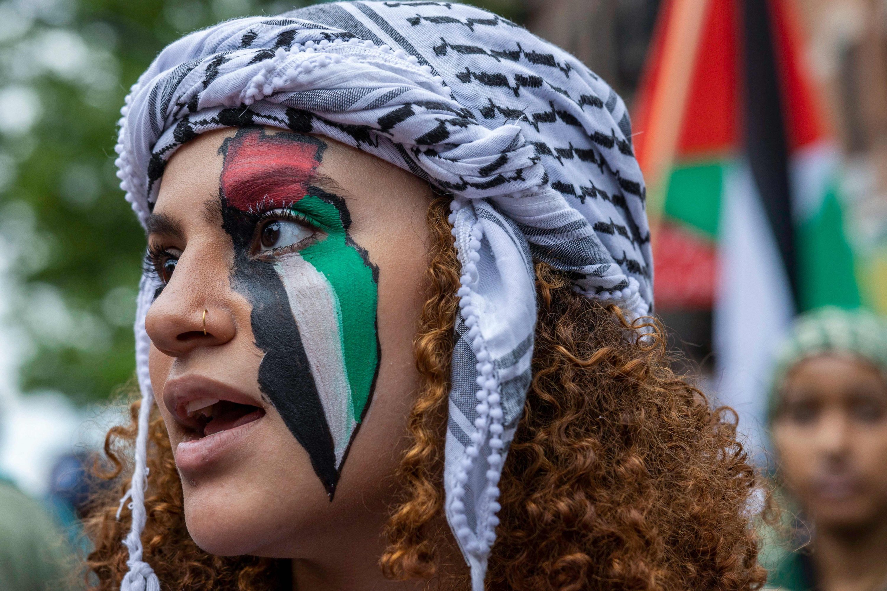 Seorang pendukung hak Palestina mengenakan warna bendera Palestina yang dilukis di wajahnya selama pawai untuk memperingati 75 tahun Nakba, atau 