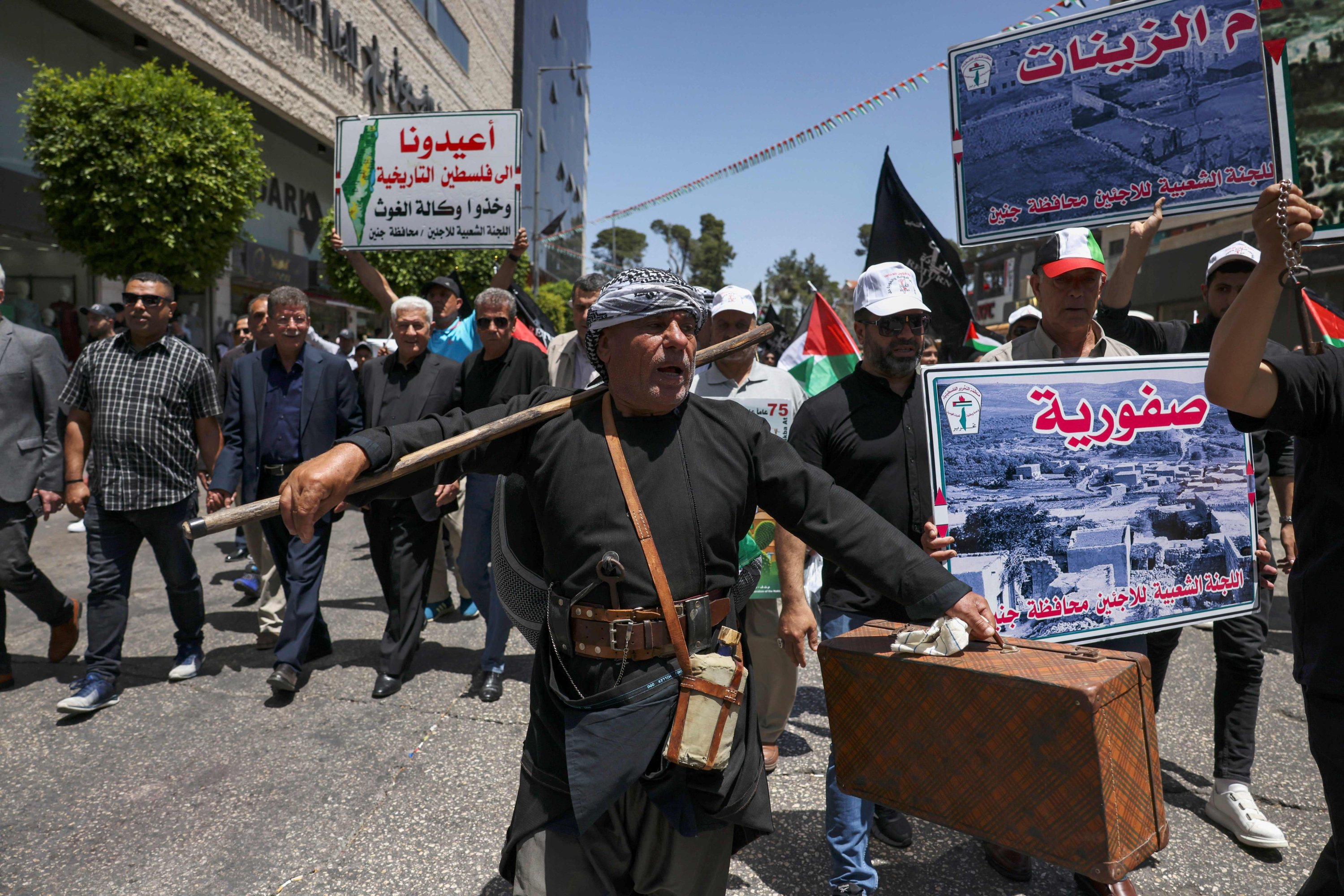 Seorang pengunjuk rasa membawa barang bawaan yang melambangkan warga Palestina yang melarikan diri atau diusir dari rumah mereka 75 tahun yang lalu selama unjuk rasa yang menandai hari 'Nakba' di pusat kota Ramallah di Tepi Barat yang diduduki, 15 Mei 2023. (Foto AFP)