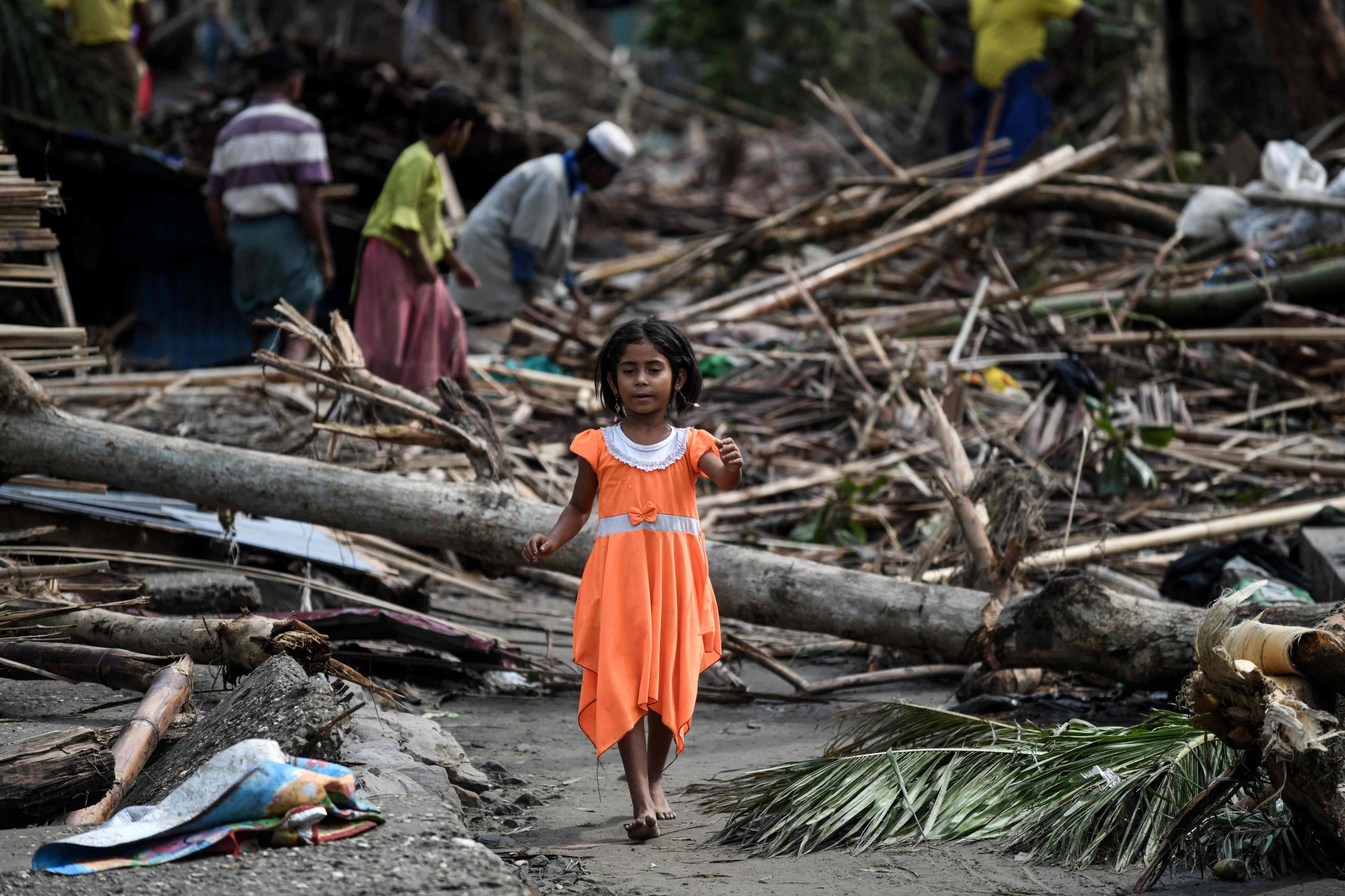 Seorang gadis berjalan melewati rumah-rumah yang hancur di kamp pengungsi Basara di Sittwe, Myanmar, 16 Mei 2023. (Foto AFP)