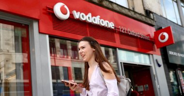 A woman holds a phone as she passes a Vodafone store in London, Britain, May 16, 2017. (Reuters Photo)