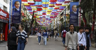 People stroll under umbrellas and posters depicting Türkiye's Founder and first President Mustafa Kemal Atatürk, the day after the general election, in Ankara, Türkiye, May 15, 2023. (EPA Photo)