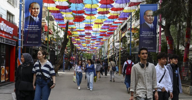 People stroll under umbrellas and posters depicting Türkiye's Founder and first President Mustafa Kemal Atatürk, the day after the general election, in Ankara, Türkiye, May 15, 2023. (EPA Photo)