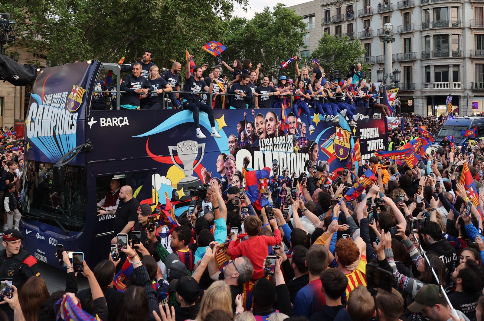 The players of FC Barcelona women football team parade aboard a open-top bus preceded by the men&#039;s team (out of frame), to celebrate their La Liga titles, Barcelona, May 15, 2023. (AFP Photo)