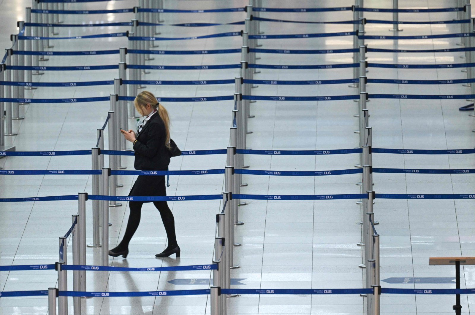 An airline employee walks between barrier tapes past a check-in counter during a strike at the airport of Duesseldorf, western Germany, April 20, 2023. (AFP Photo)