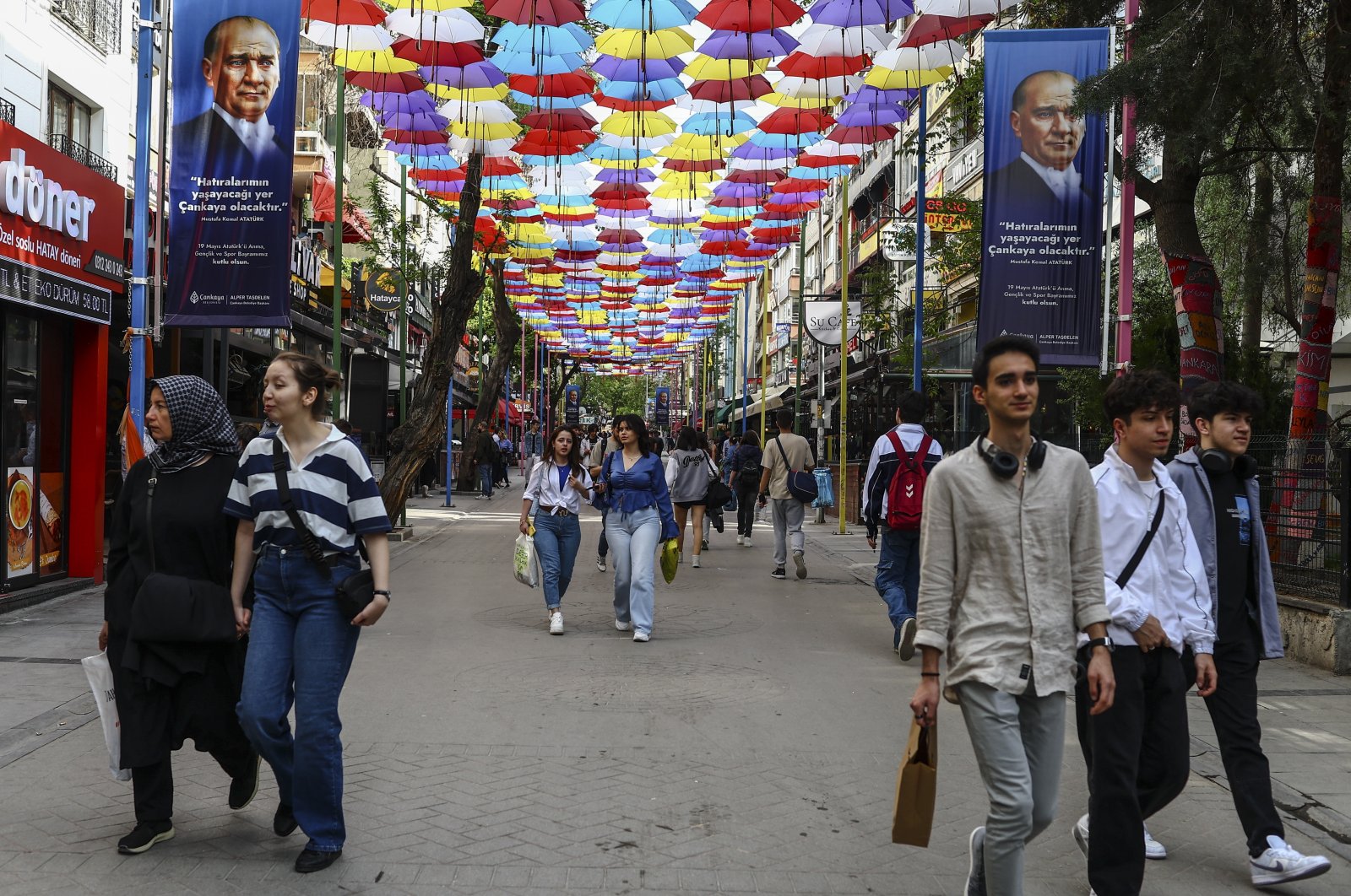 People stroll under umbrellas and posters depicting Türkiye&#039;s Founder and first President Mustafa Kemal Atatürk, the day after the general election, in Ankara, Türkiye, May 15, 2023. (EPA Photo)