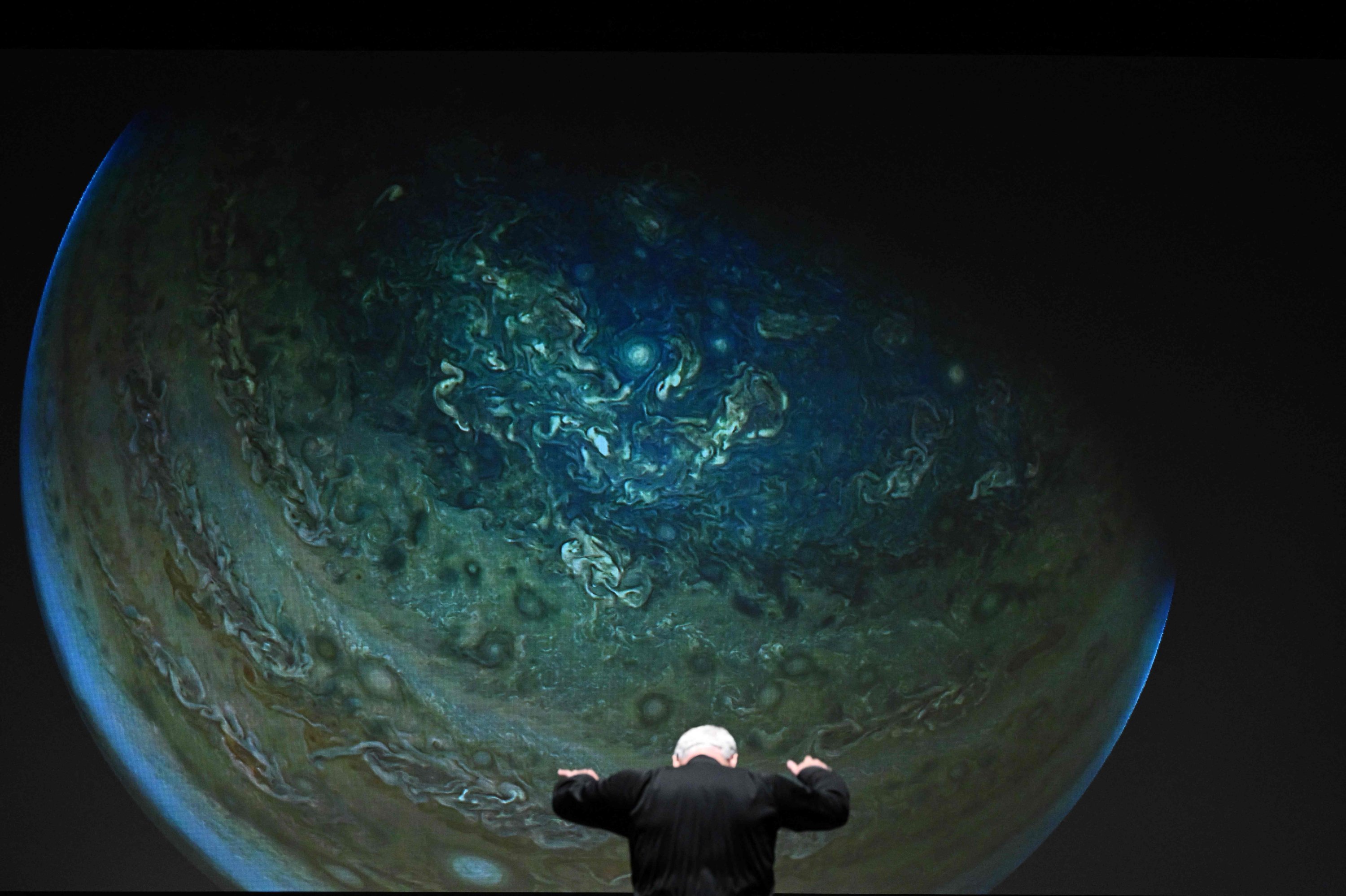 Di depan gambar NASA yang diproyeksikan di layar, Direktur Musik National Philharmonic dan Konduktor Piotr Gajewski berlatih 